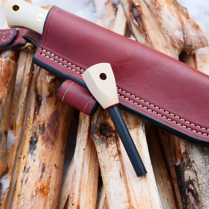 A matching bushcraft firesteel from ivory paper micarta with a chestnut brown leather sheath behind it