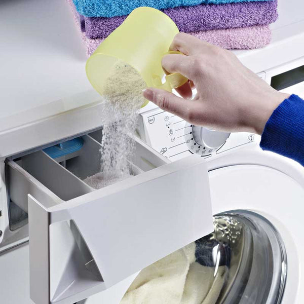 hand pouring laundry detergent into machine