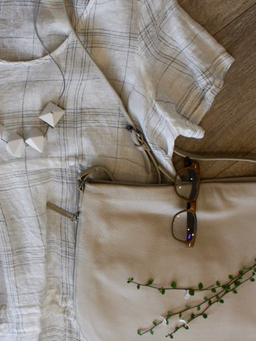 flat lay of Chocolat garment, Elk bag and necklace, available at Hall Greytown