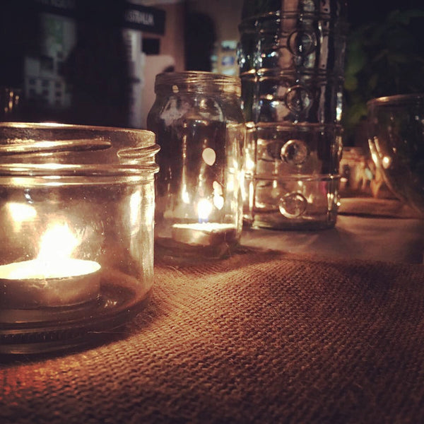 Image of tealights in jars on a table in a dark room