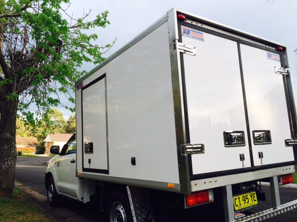 New ute parked under a tree with a large insulated box on the back