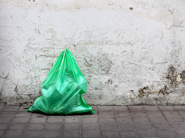 Image of green rubbish bag against a wall