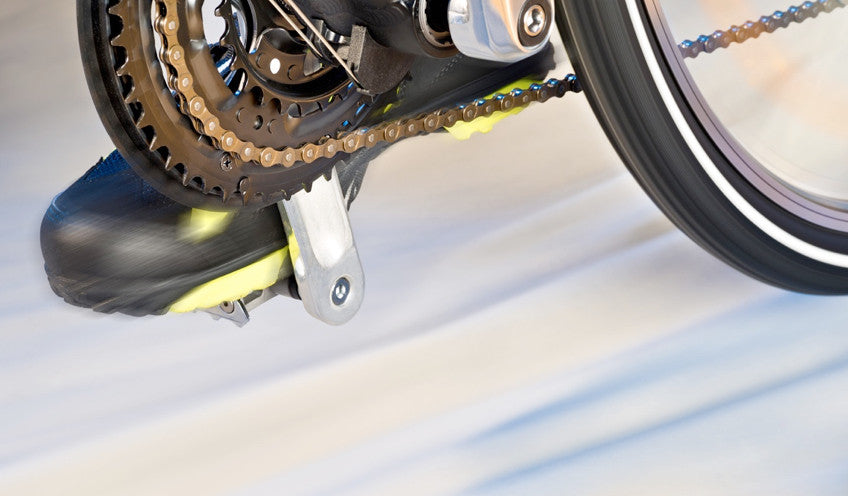 View of a bicycle in motion with a focus on the chainrings, chain, crankshaft, and pedal