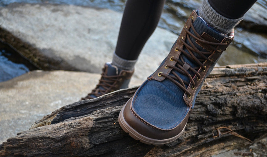 Hiker wearing Lems Boulder Boots with one foot resting on a log