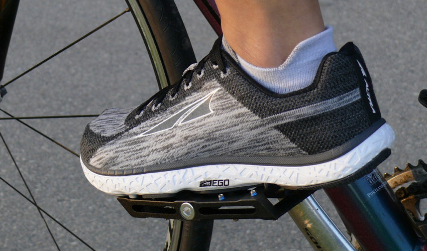 Side view of an Altra athletic shoe resting on a Black Catalyst Pedal