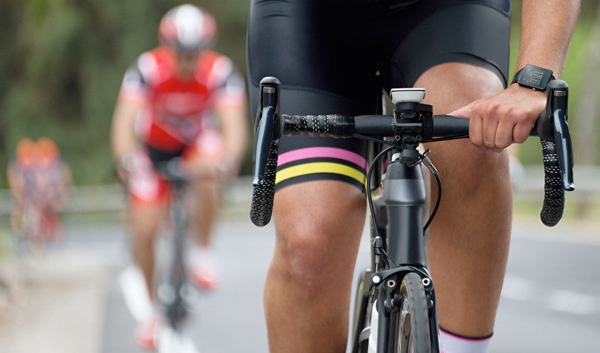 Head-on view of a road cyclist pedaling his bike with competitors in the background