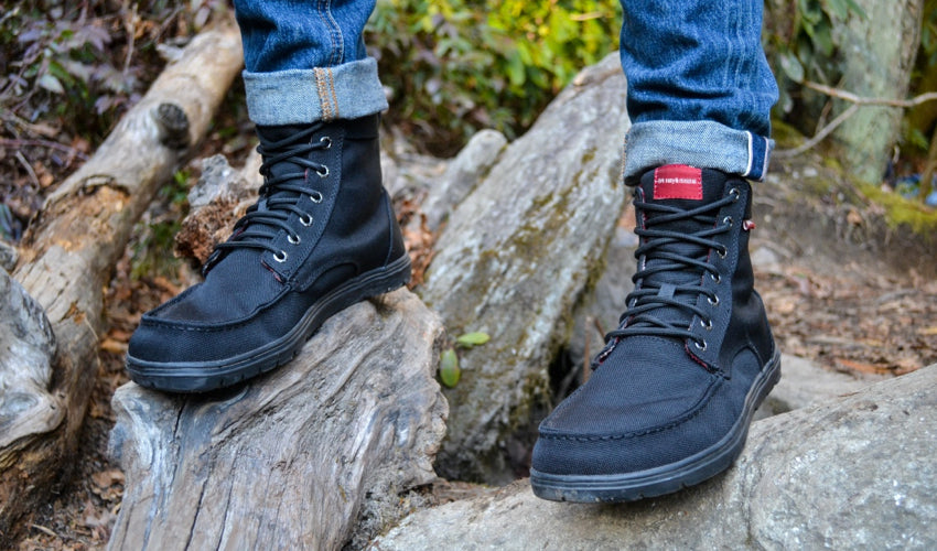 Person wearing Lems Boulder Boots in Black standing on a gnarled piece of driftwood