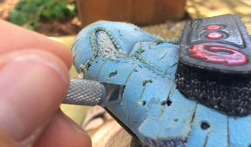A person slicing the sidewalls of a road cycling shoe's toe box with a scalpel