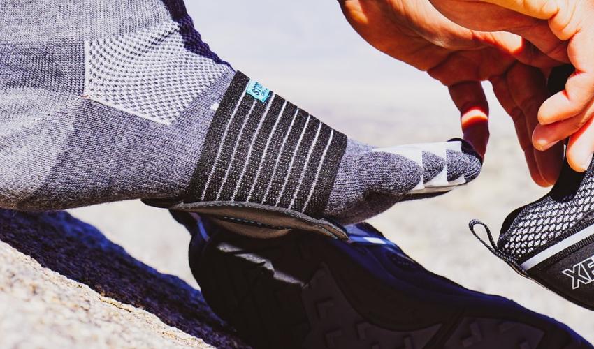 A close-up view of a pair of Black Strutz Pro foot pads on the foot of a person also wearing toe socks and Correct Toes