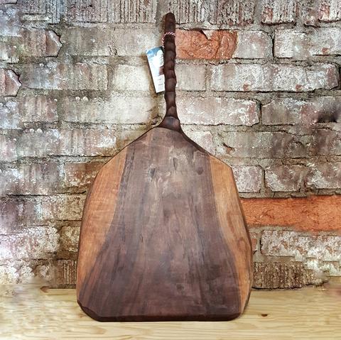 A pizza paddle with contrasting stripes of light and dark walnut wood.
