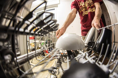 Person loading a bowl into a dishwasher.