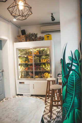 Fridge full of fruits and vegetables and other food in a white kitchen