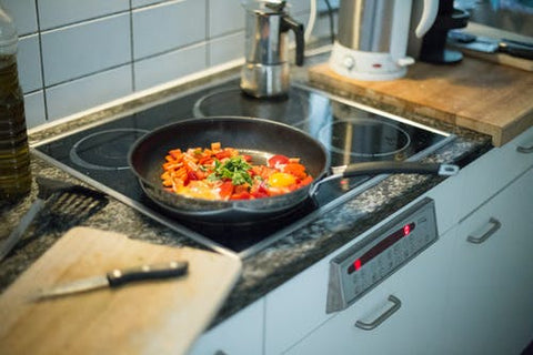 Medly of food in a skillet with a cutting board and knife to the side.