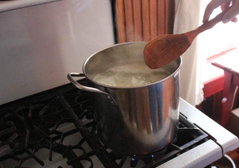 Pot on vintage stovetop with a wooden spoon ladle reaching into it.