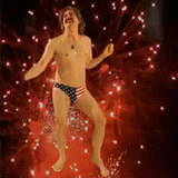 man in american flag speedo dancing in front of fireworks