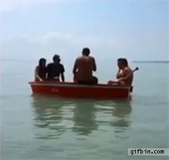 several men falling out of small red boat