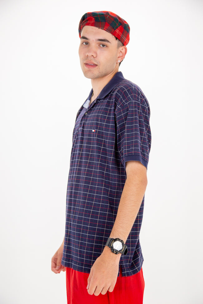Standard polo in a navy hue with red, green, yellow and white grid across the whole top. Features the Tommy flag logo embroidered on the left chest.