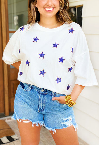 Like a star sequin top. White tee with blue sequin stars outlined in gold.