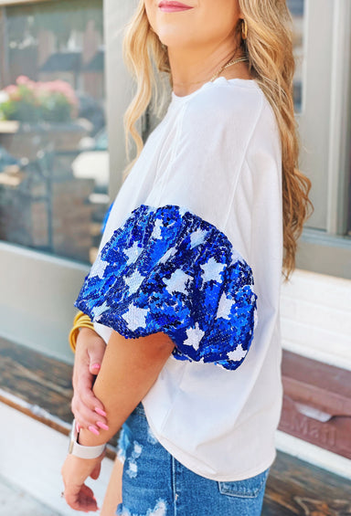 Stars Align Top, It is a white tee with eye-catching blue sequin puff sleeves that are adorned with white sequin stars