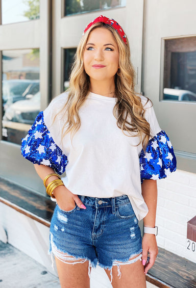 Stars Align Top, It is a white tee with eye-catching blue sequin puff sleeves that are adorned with white sequin stars