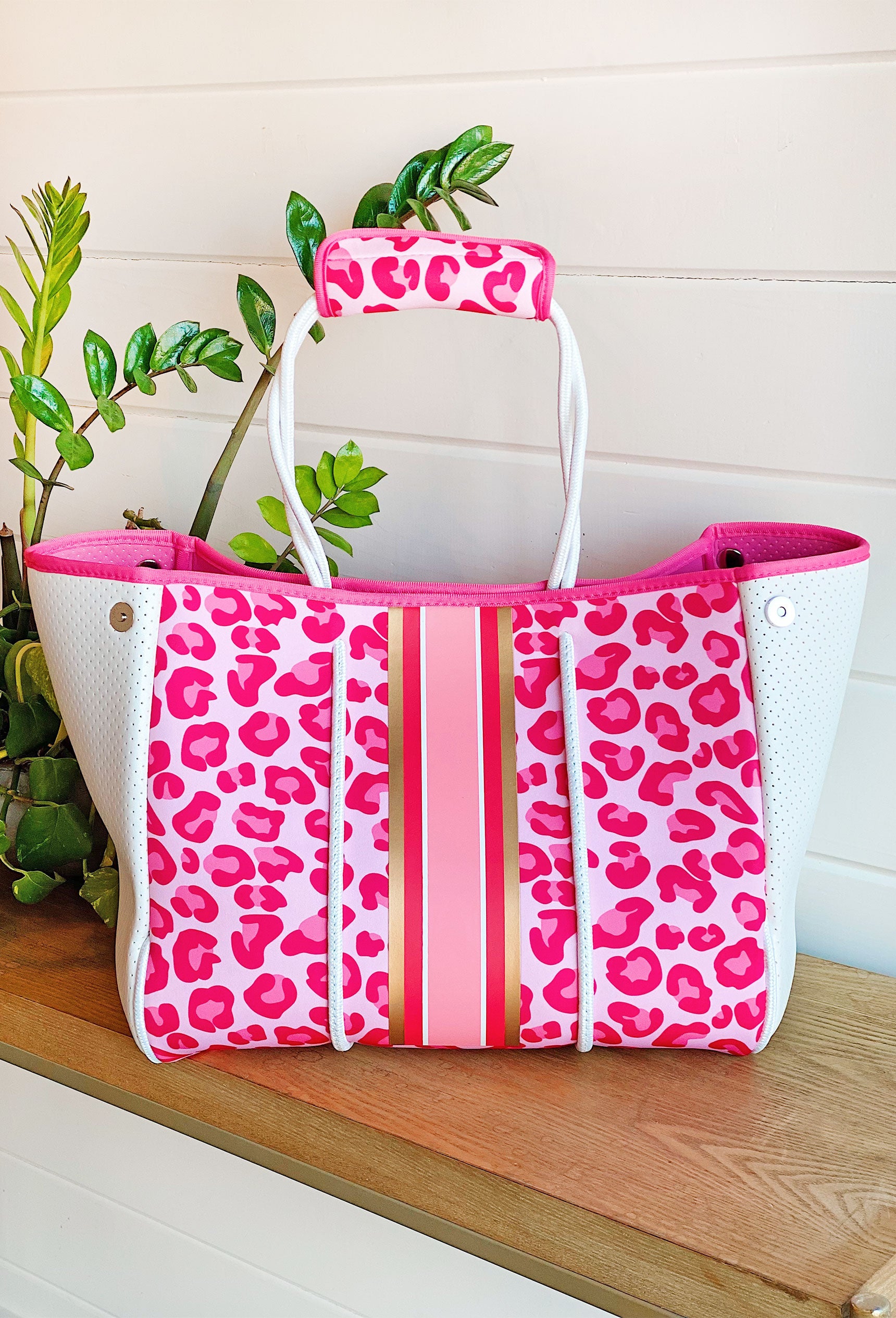 The Brianna Neoprene Tote, hot pink and light pink cheetah with pink and gold stripes down the middle, white handles and detailing, comes with handle strap