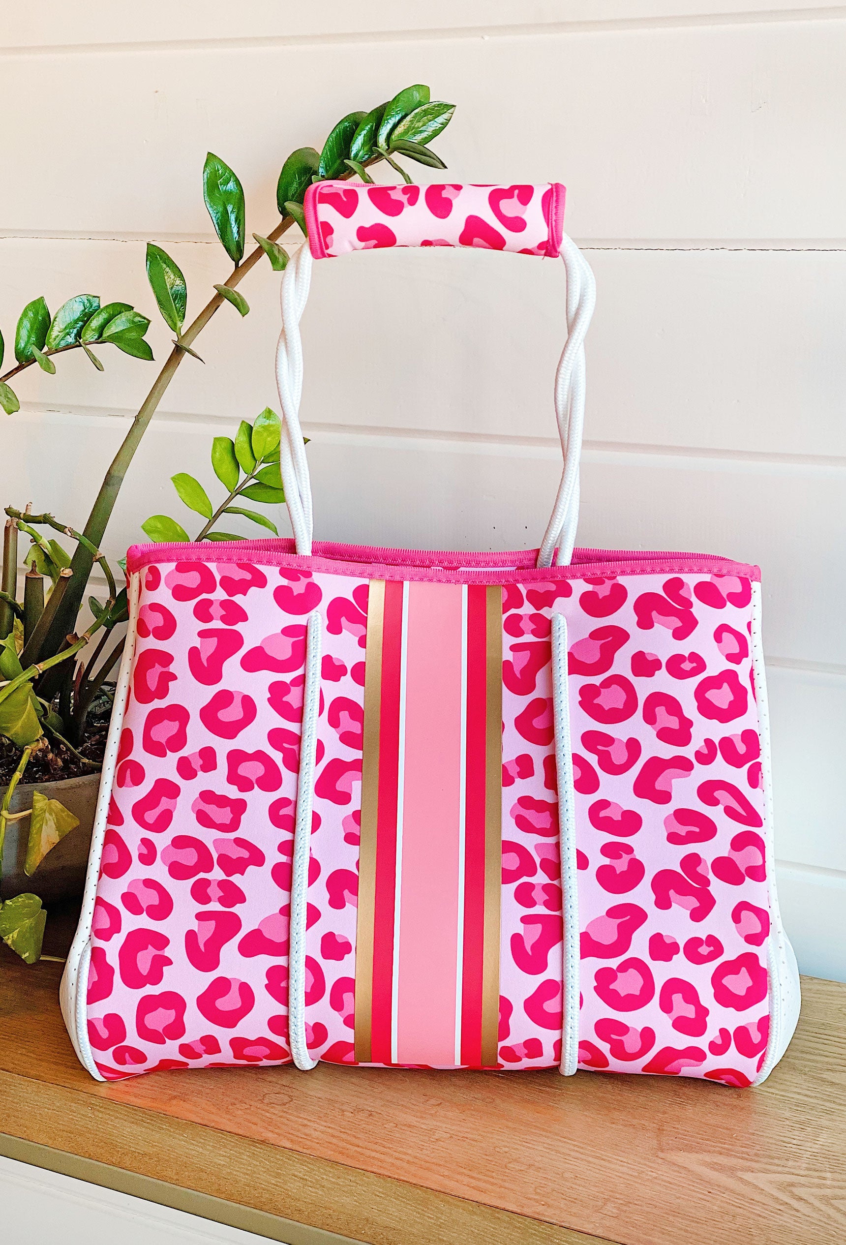 The Brianna Neoprene Tote, hot pink and light pink cheetah with pink and gold stripes down the middle, white handles and detailing, comes with handle strap