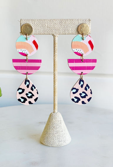 Tropical Bliss,  lightweight earrings feature three tiers of unique, painted designs. One tier features a colorful abstract print, while the second contains a pink striped print and the third displays a sassy leopard print. The wooden design exudes summery cheer