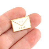 Envelope Enamel Pin Badge with Kawaii smiling face - held to show scale