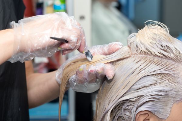 Blonde Woman Getting Her Hair Color Treated At Beauty Salon | ISA Professional