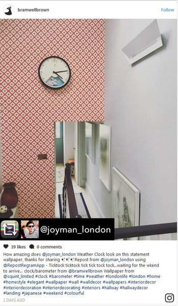 Clock with red wall paper behind in hallway