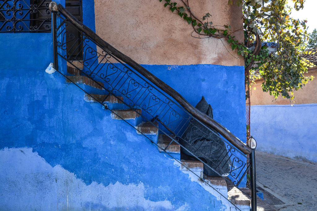 Street Scenes in Chefchaouen, Morocco by Sophee Smiles - Hooded Man Sitting on Blue Stairs