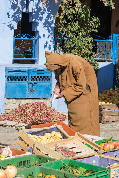 Street Scenes in Chefchaouen, Morocco by Sophee Smiles - Hooded Man Bending Over Vegetables