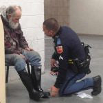 unformed man kneeling in front of seated homeless man