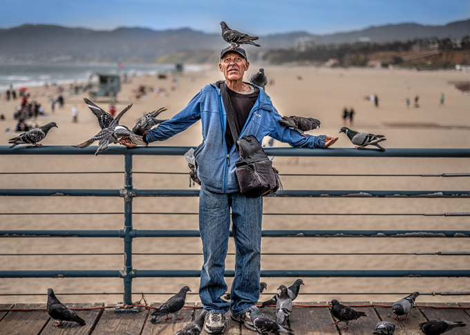 Image taken by Michael Schoenfeld of man at beach surrounded by pigeons 