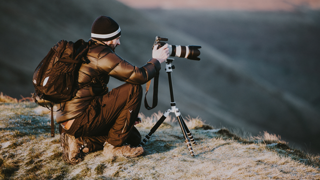 A photographer on a mountain taking a photo with camera and tripod