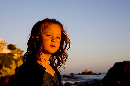 Little girl with curly hair at beach during sunset