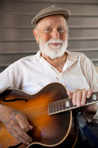 Old man with white beard sitting with a guitar