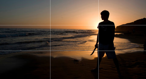 Boy standing on beach at sunset with rule of thirds grid overlay