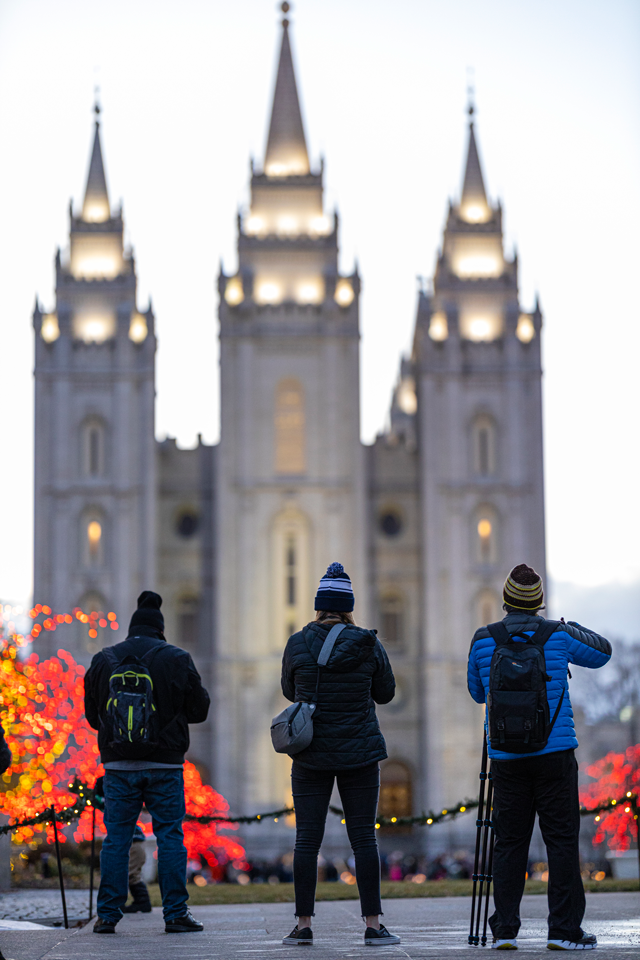 three people getting ready to take photos of the salt lake city temple and temple lights 