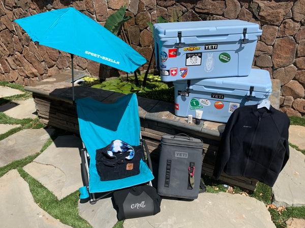 A sports-brella and chair with two Yeti Coolers on the beach.
