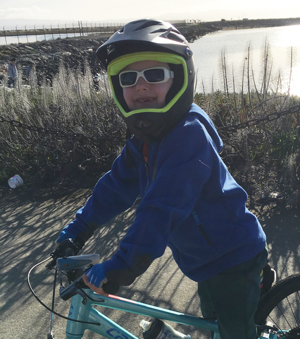 Lynell's son with a full face helmet on while on his bike.