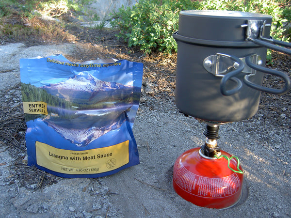 Backpacking food pack next to a jet boil stove boiling water.