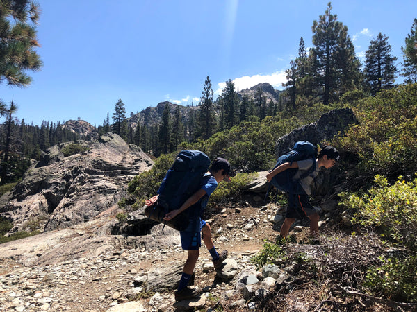 Susan's two sons wearing their backpacks and hiking.