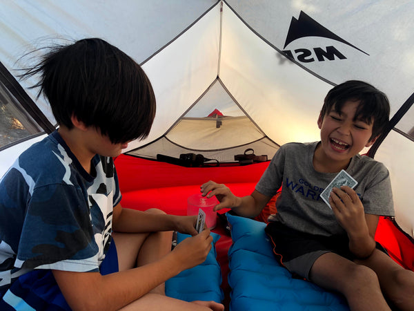 Susan's sons playing cards in a tent.