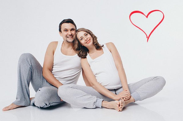 Pregnant couple sat on floor in yoga gear