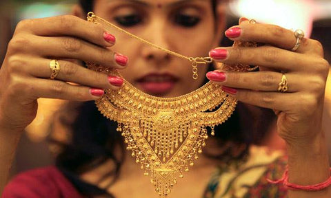 Lady holding up and looking at an Indian gold or 22ct gold neckace