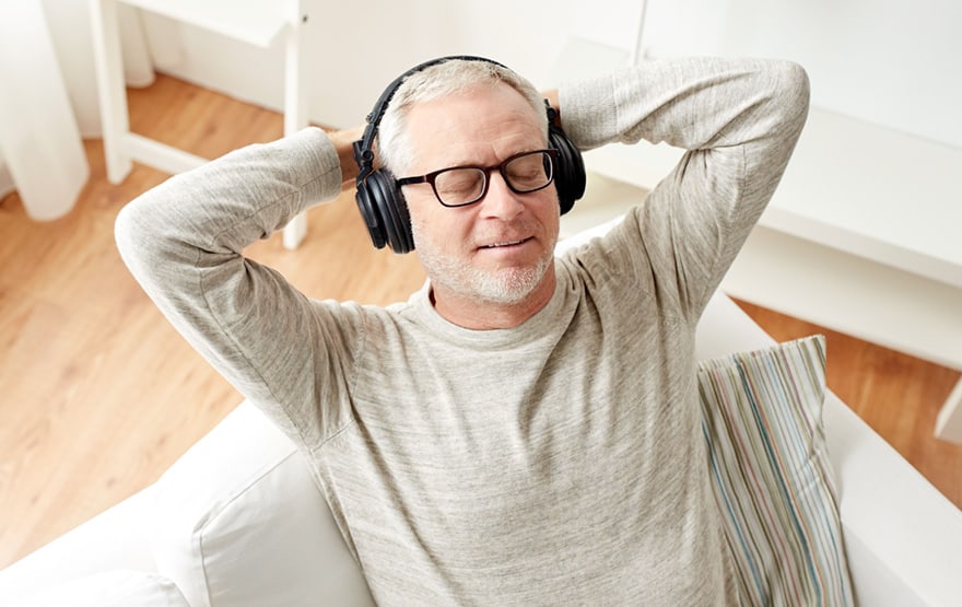 older man listening to music with headphones