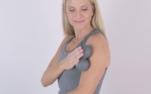 Middle age woman massage her shoulder using peanut massage ball
