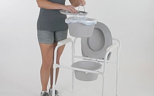 woman removing pail from folding commode