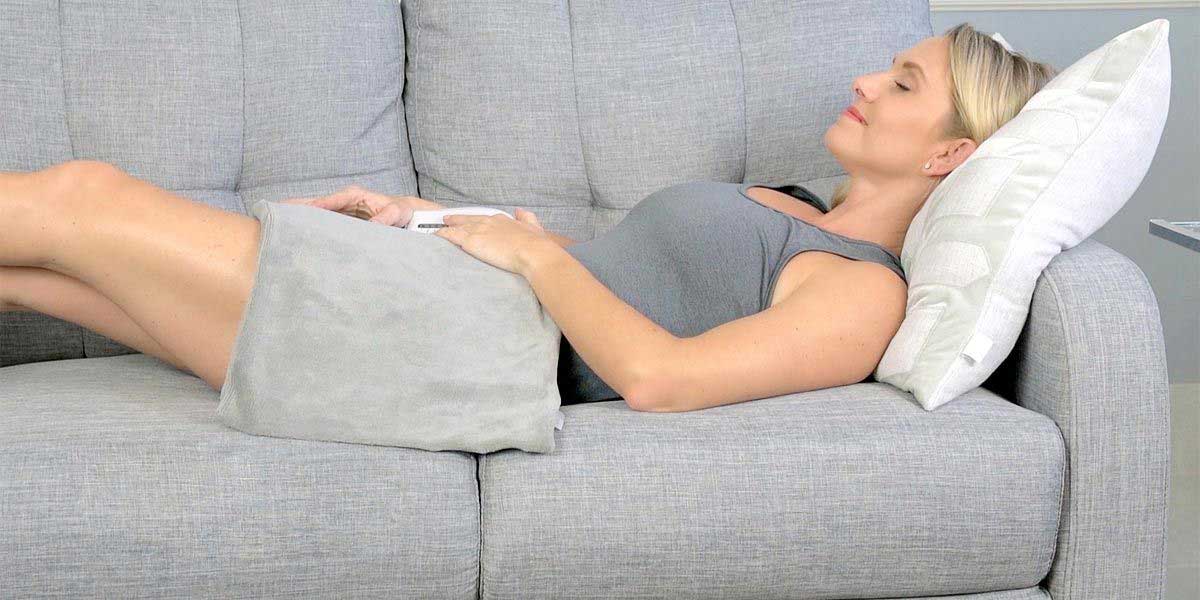 Middle age woman sleeping in the couch with heating pad on her lap